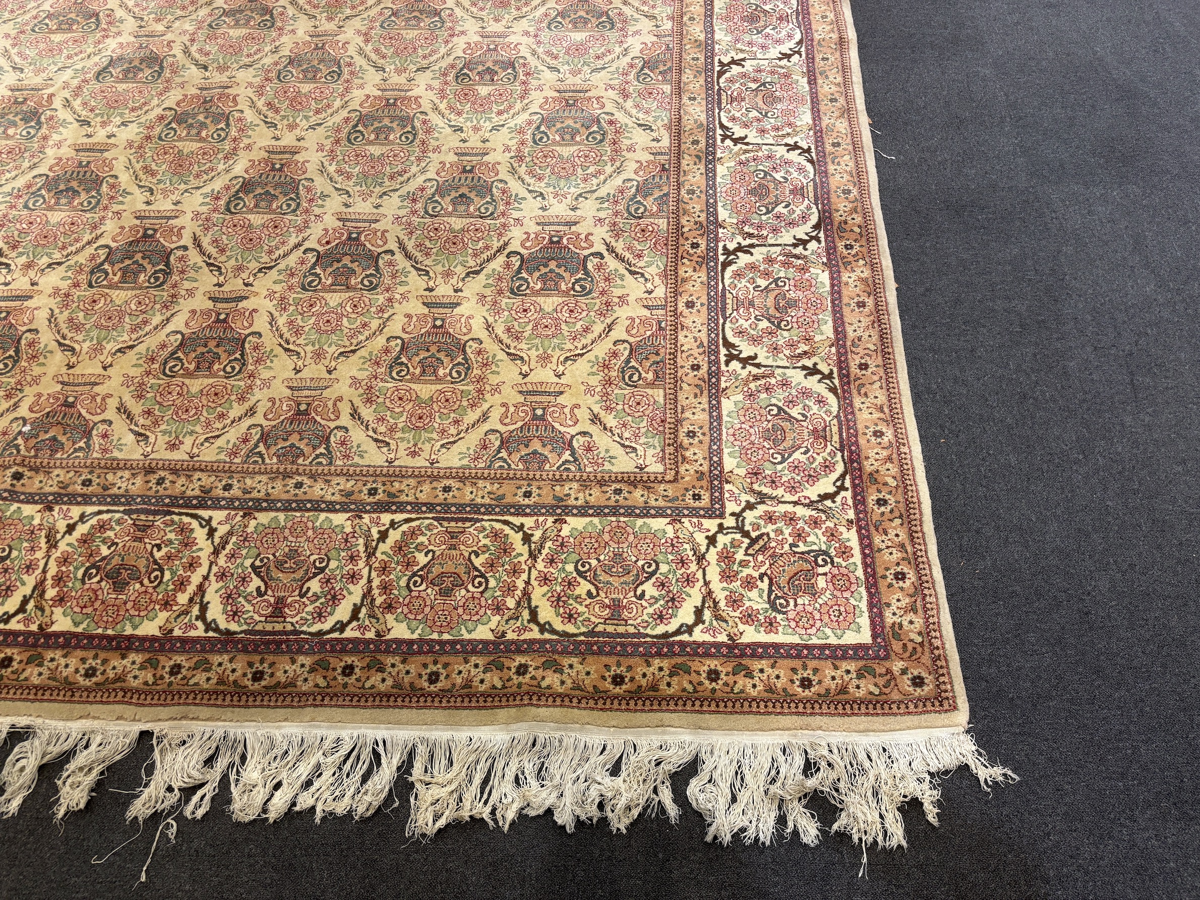 A North West Persian ivory ground carpet, woven with rows of flowering urns, 400 x 298cm